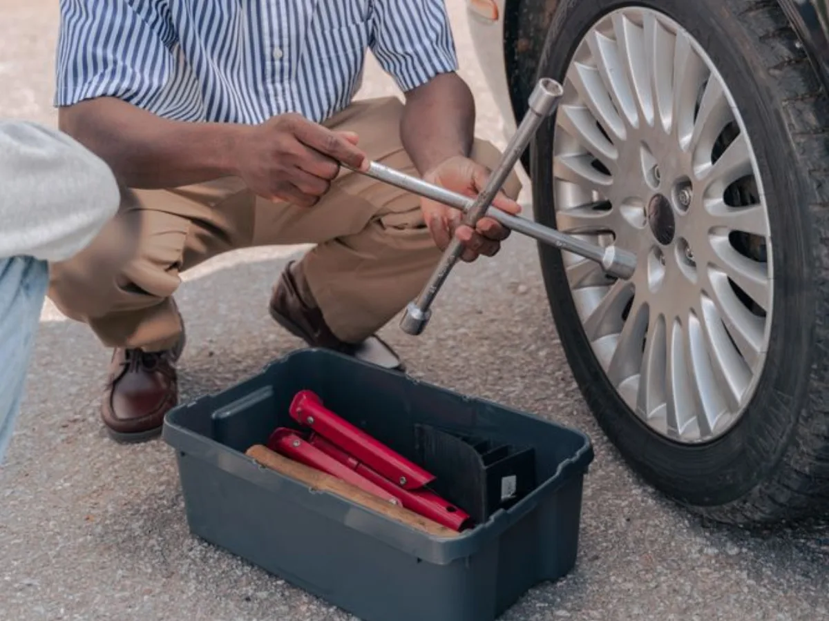 Des mains utilisent une clé de roue près d’un pneu à l’extérieur
